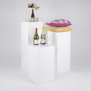 Three White Display Plinths With A Number Of Items On Display.