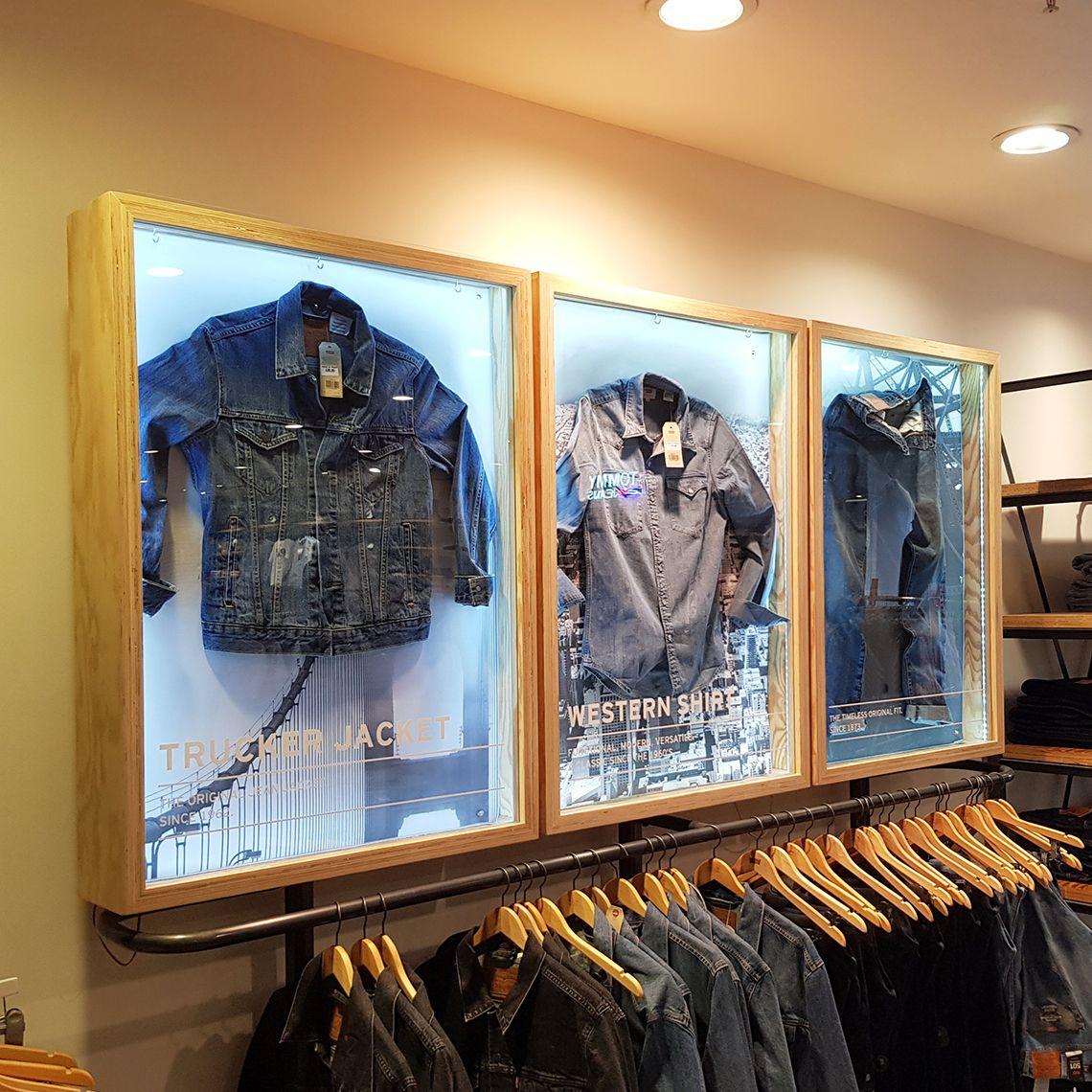 Wall Mounted Illuminated jacket display case in clothing store with custom digital branding on the front.