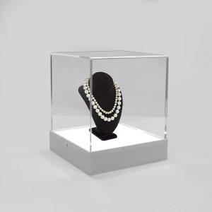 A white illuminated display case with a necklace on display.