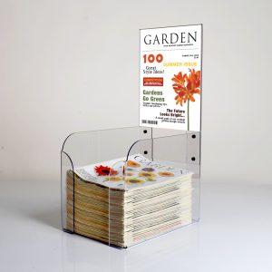 A countertop magazine stand with magazines inside and a header with removeable graphics.