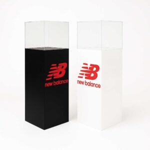 One white and one black product display plinth with new balance branding on one side of each plinth.