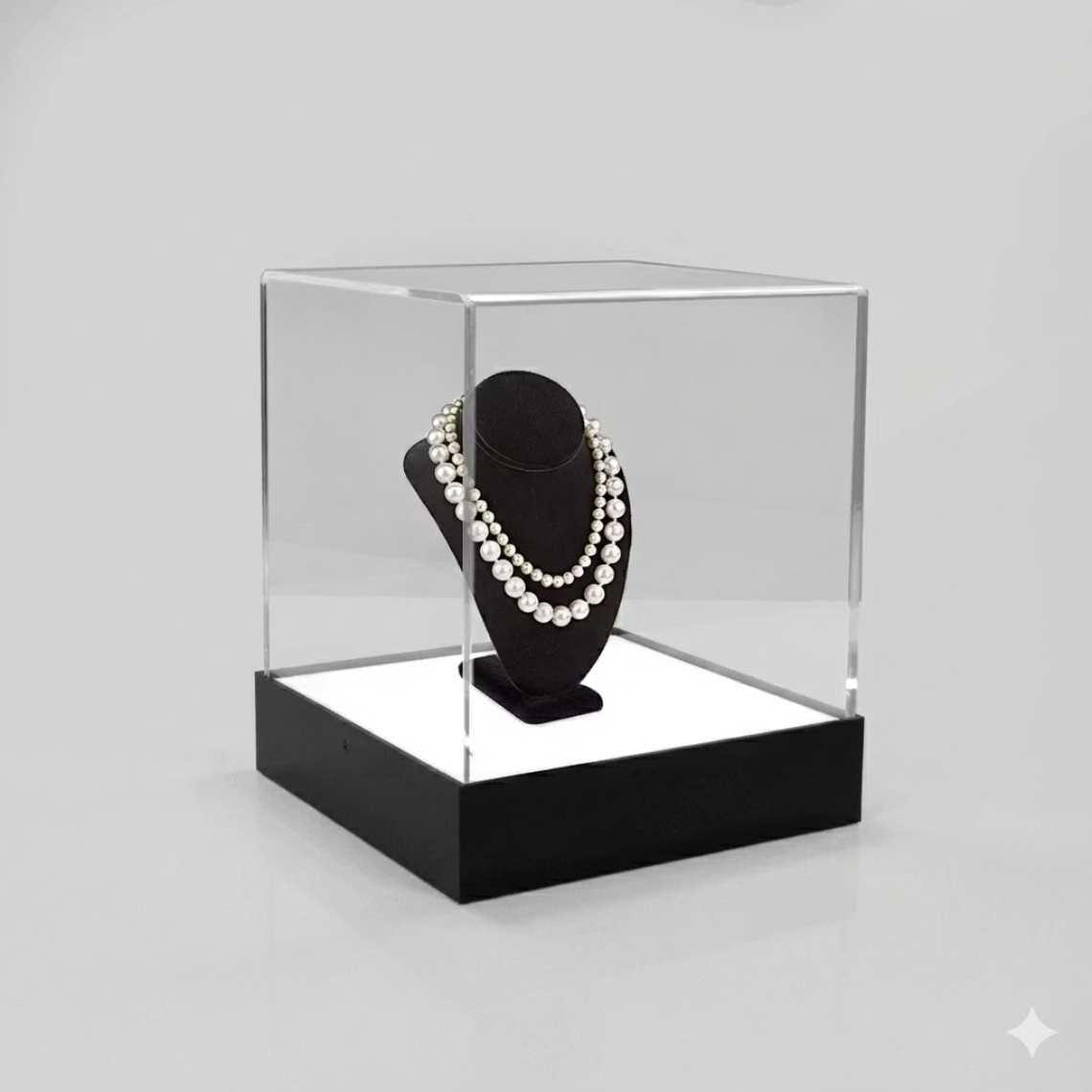 An illuminated display cabinet with a black base and a necklace on display.