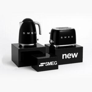 Black gloss display plinths showcasing SMEG kettle and toaster with branded and “new” graphics, used for premium retail product presentation.Black gloss display plinths showcasing SMEG kettle and toaster with branded and “new” graphics, used for premium retail product presentation.