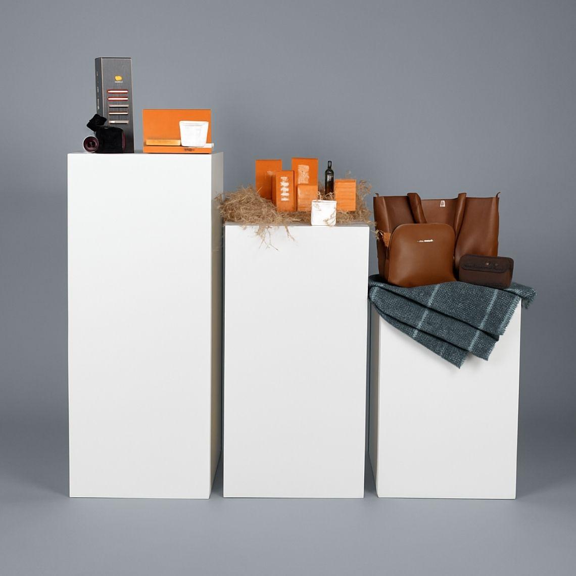 Three white display plinths with tiered heights.