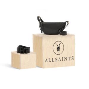 Black leather AllSaints crossbody bag and black belt displayed on light wooden product display risers with AllSaints branding.