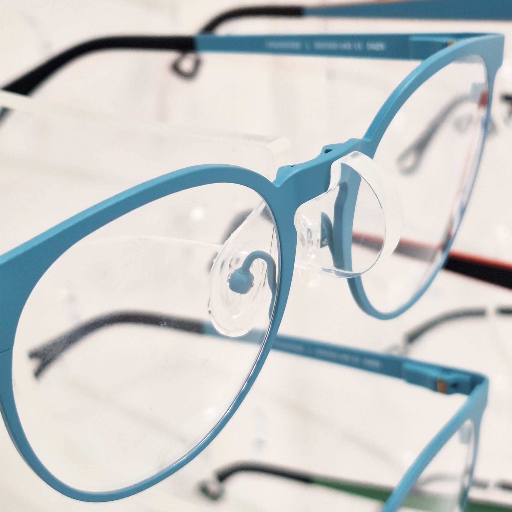 Close-up of acrylic eyeglass holder system on optical display board, showcasing secure frame support design for retail eyewear presentation