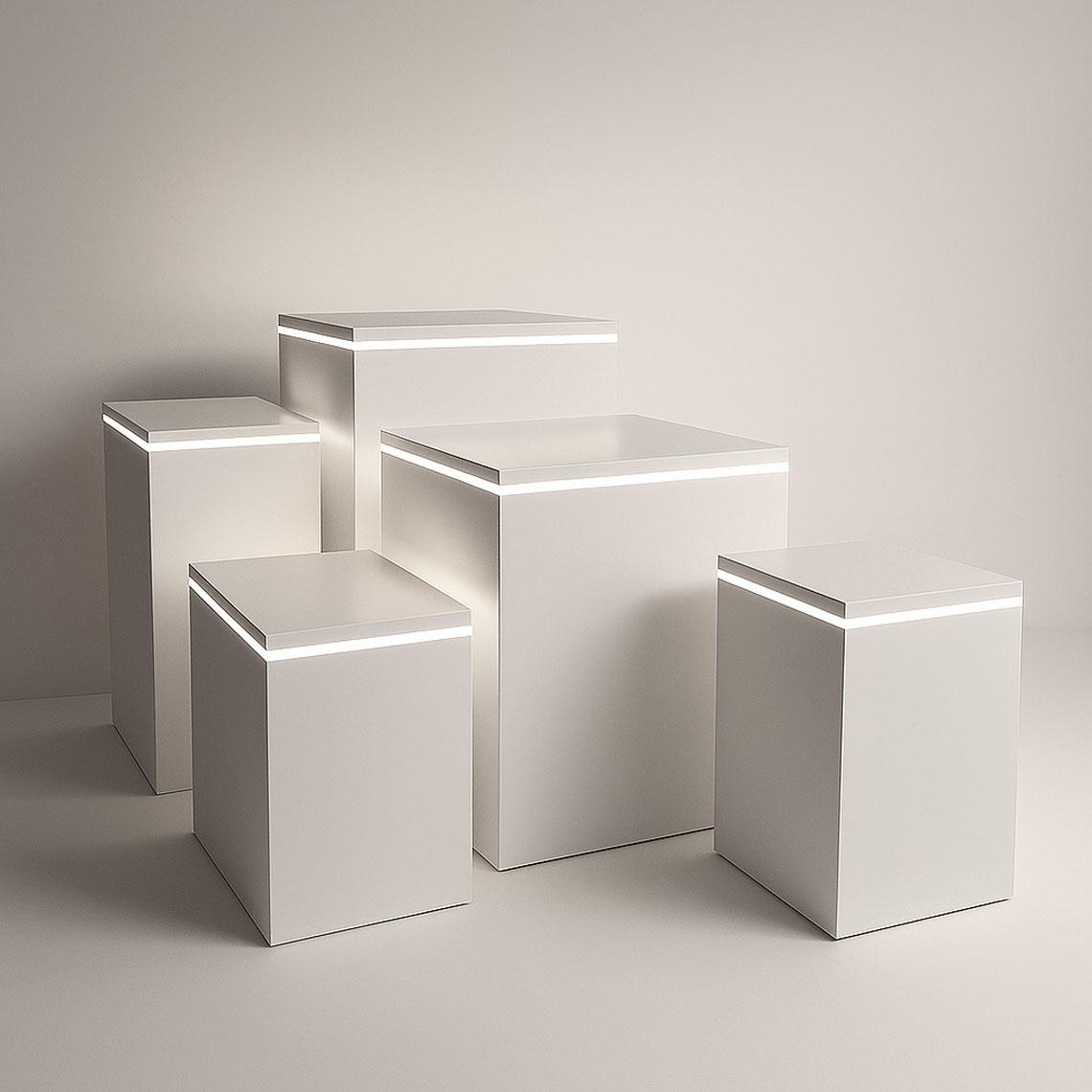 Collection of five white satin display plinths featuring subtle LED illumination around the top edges, presented in a soft-lit studio environment.