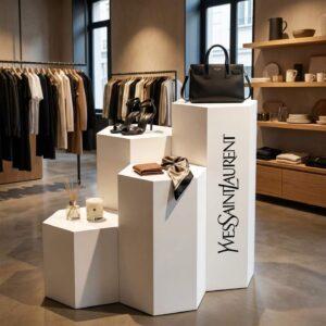 Hexagonal plinths in a clothing and homeware store with Yves Saint Laurent branding down the side and accessories on display.
