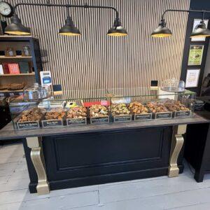 A bespoke glass sneeze guard on a tabletop with fudge on display.
