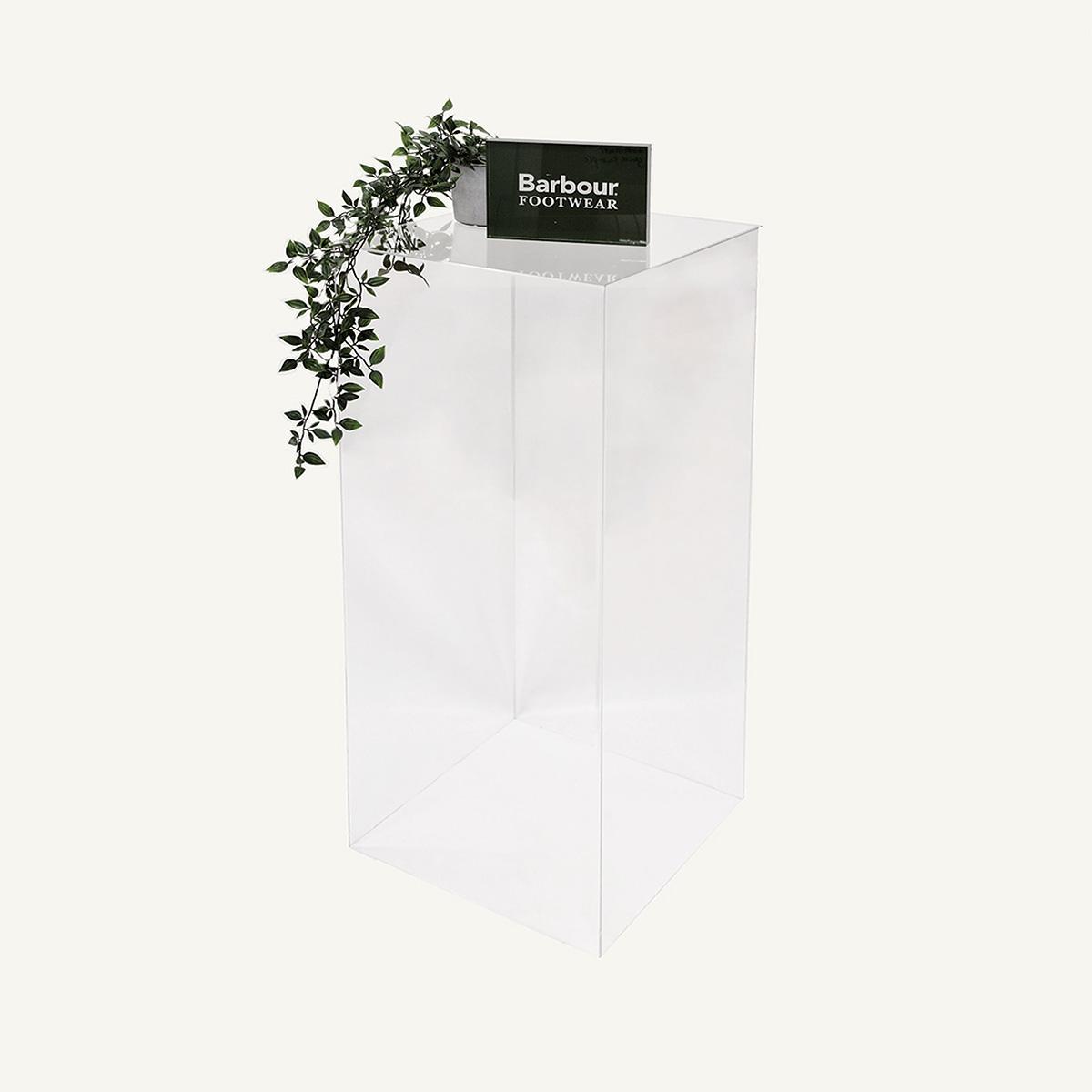 Clear Acrylic Plinth with Barbour branding block and plant on display.