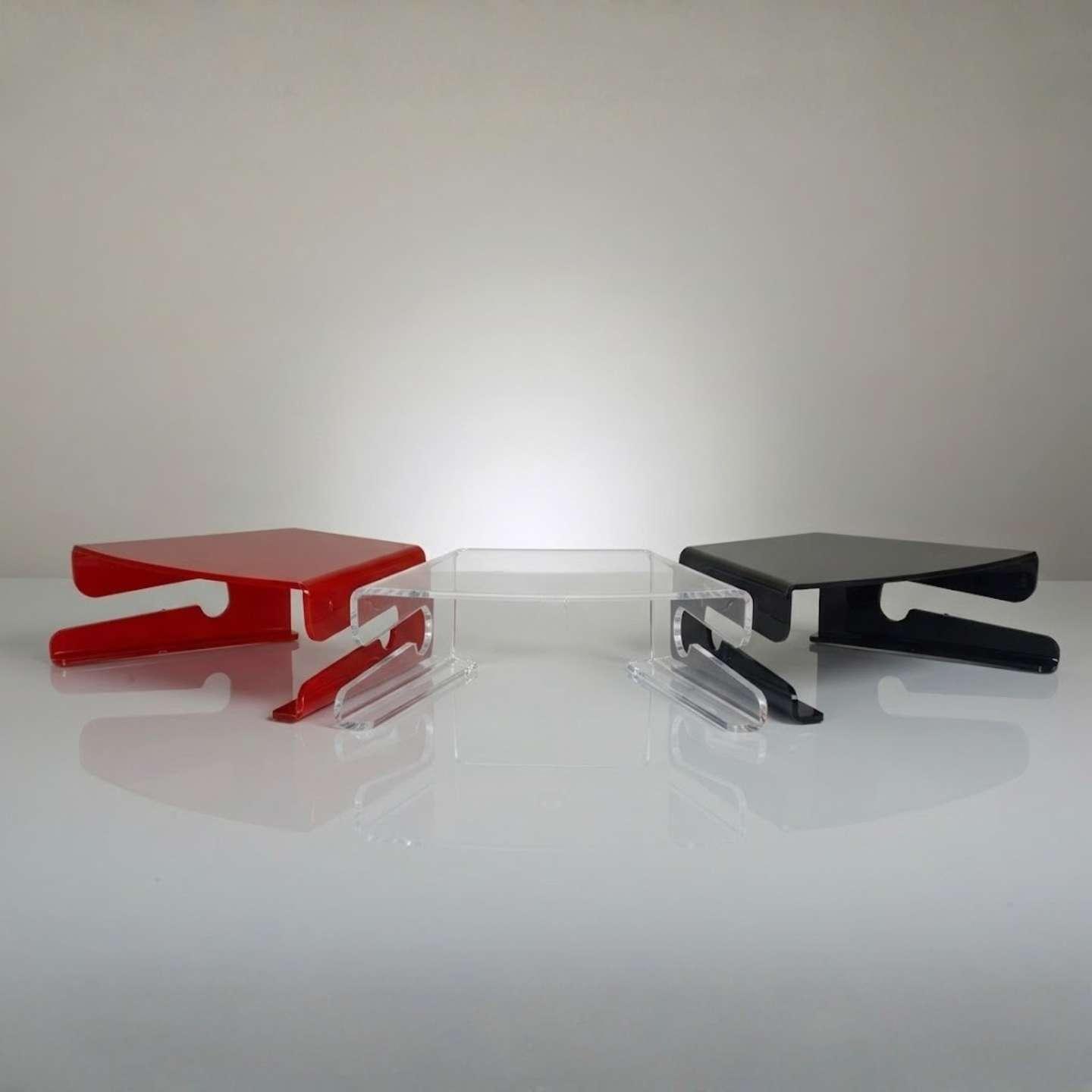 Three acrylic monitor stands in clear acrylic, red and black.