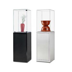 A lockable black glass display case plinth and a silver glass display case plinth, one features a lockable hinged door on the glass display case and the other features a fully sealed display case.