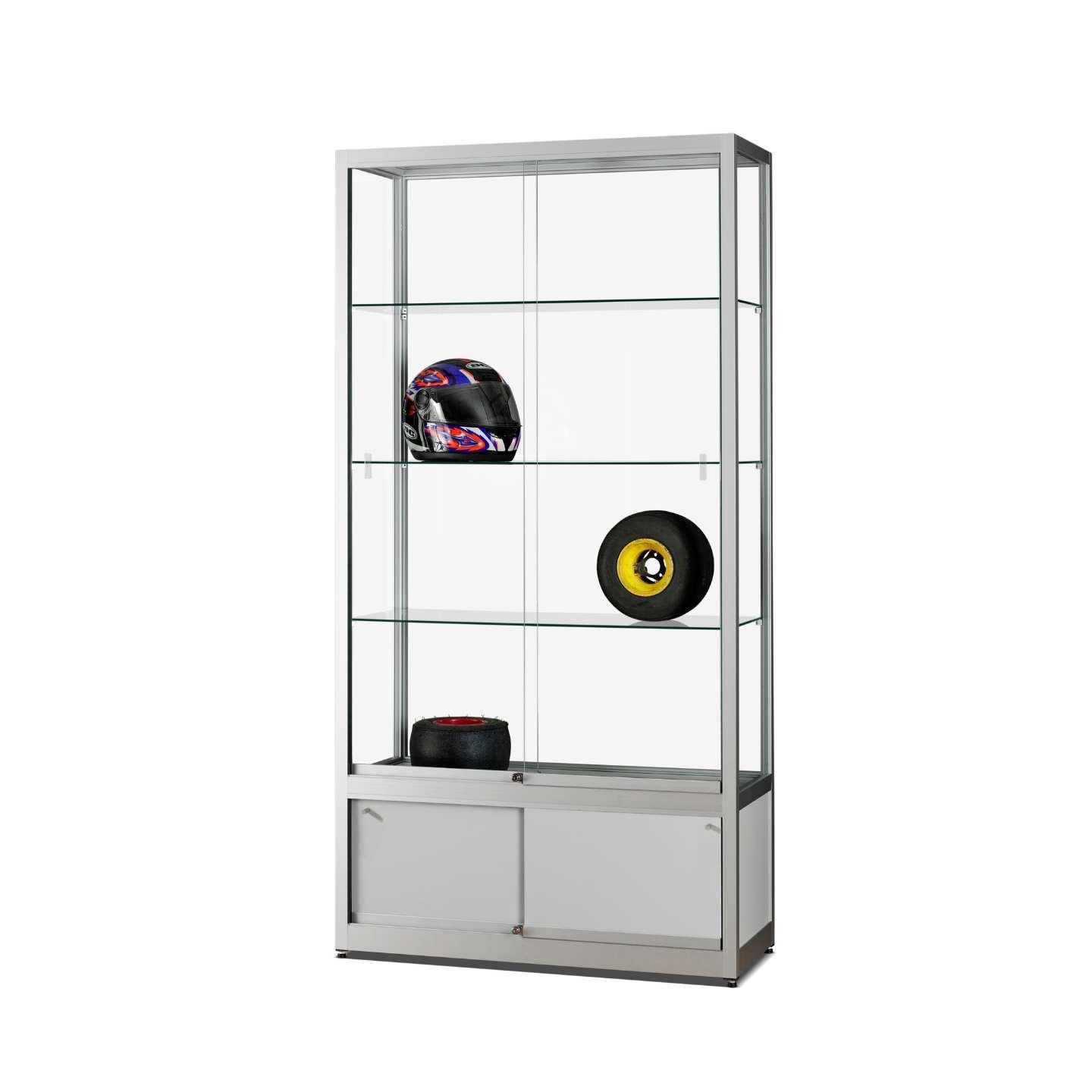 A silver display cabinet with sliding doors, storage, a helmet and tyres on display.