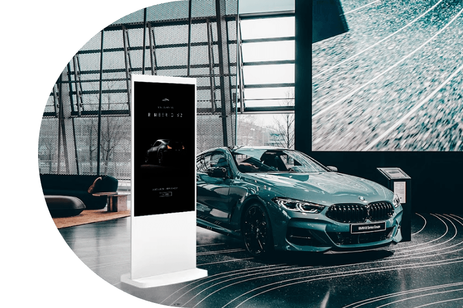 Floor standing white digital screen in car dealership.