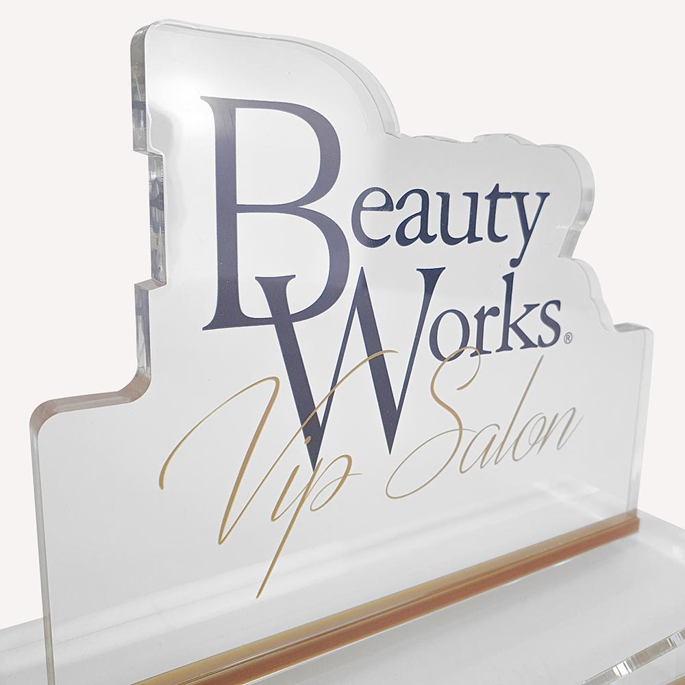 A close up of a solid clear acrylic, custom made award with "beauty works" logo on the front.