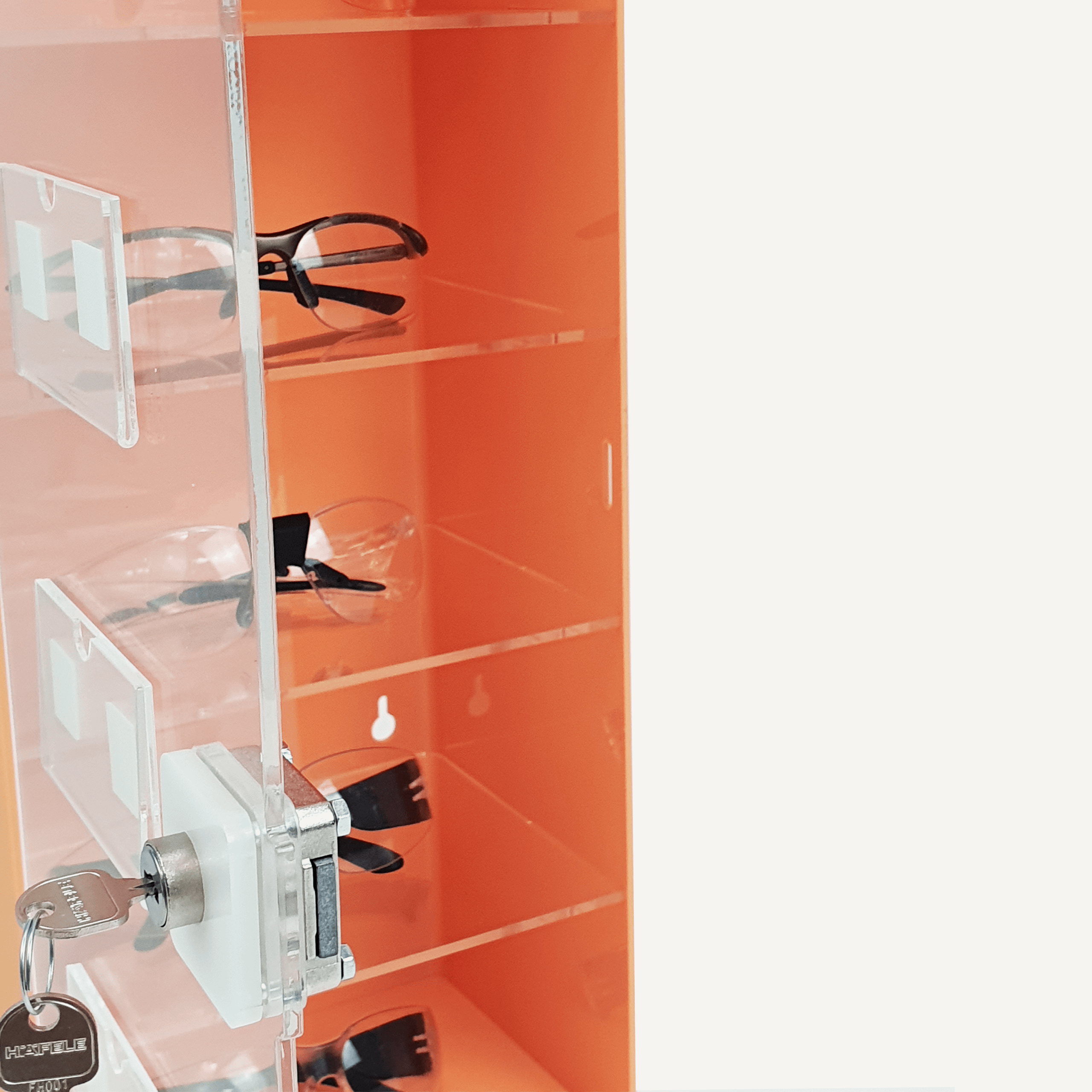 A close up of an orange PPE storage cabinet with safety goggles inside, and an open clear door with a lock and key.