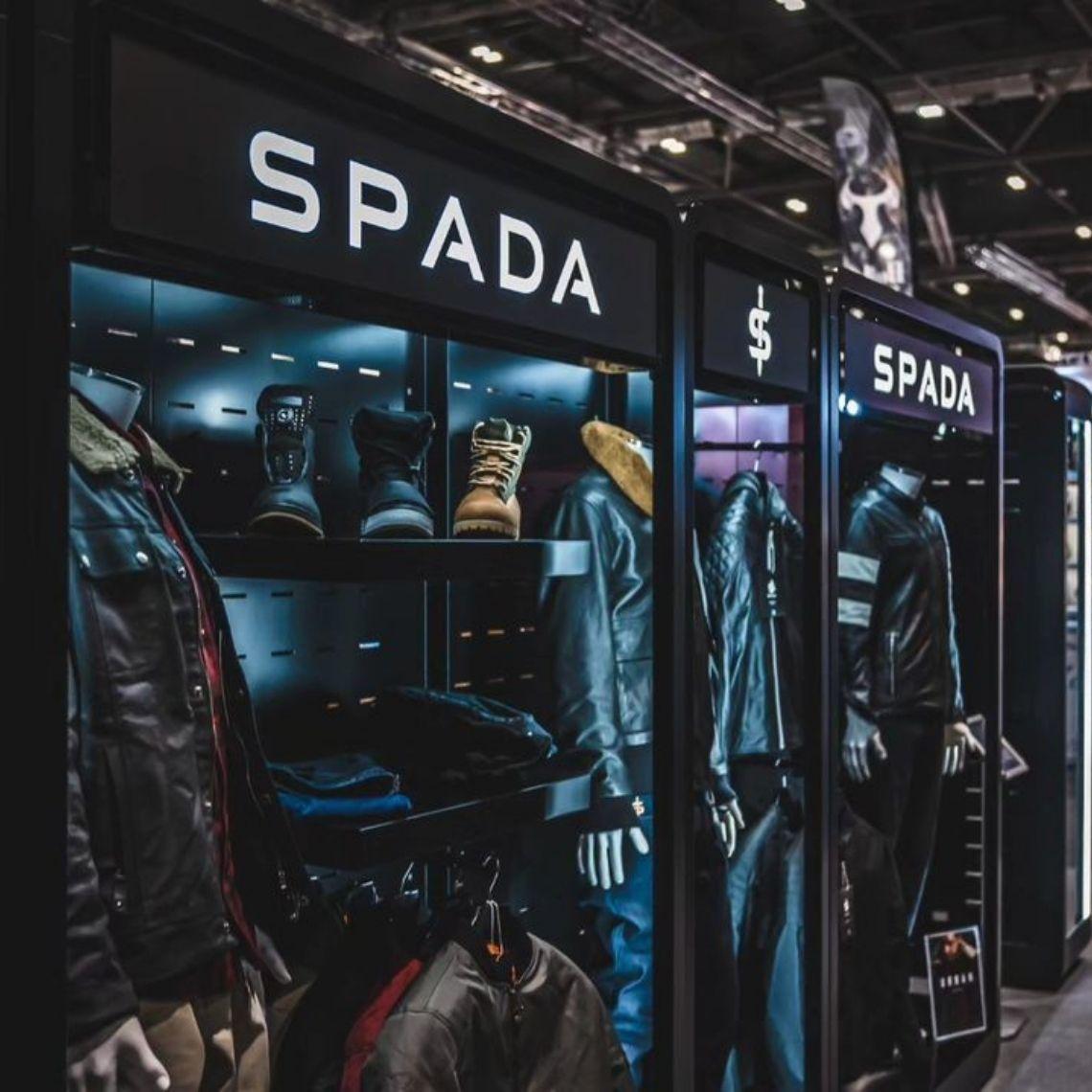 Close up corner angle of a Feridax Spada exhibition retail display, showcasing mannequins, clothing and shoes under lighting.