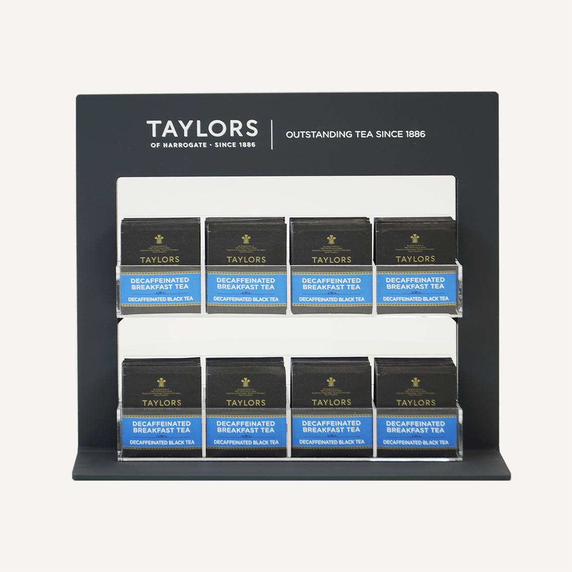A front facing view of a black Taylors of Harrogate tea bag pos display stand with custom branding and clear acrylic tea bag holders.