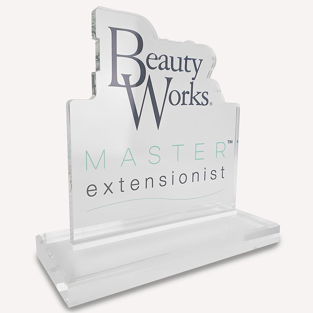 A solid clear acrylic, custom made award with "beauty works master extensionist" logo on the front.