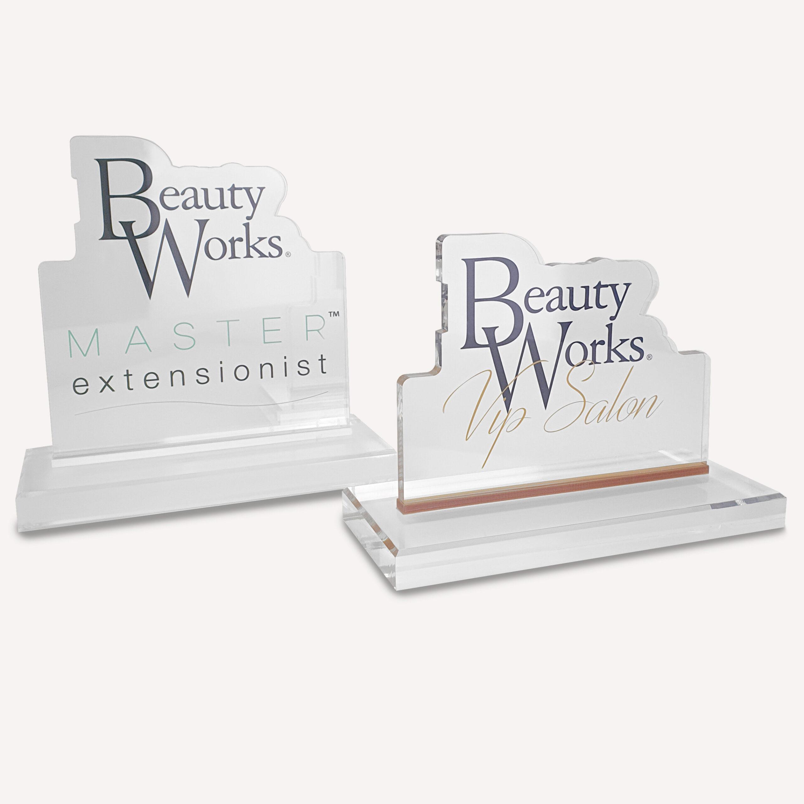 Two solid clear acrylic, custom made awards with "beauty works" logo on the front.