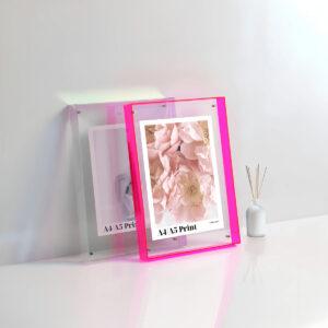 Translucent tinted clear & pink floating frames on a countertop with a5 prints displayed.