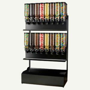 A front facing view of a black and clear freestanding bulk candy dispenser with 16 containers full of different sweets.