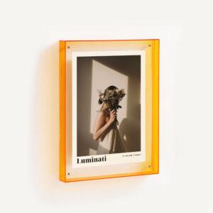 Translucent orange floating frame with fashion print displayed mounted on a wall.