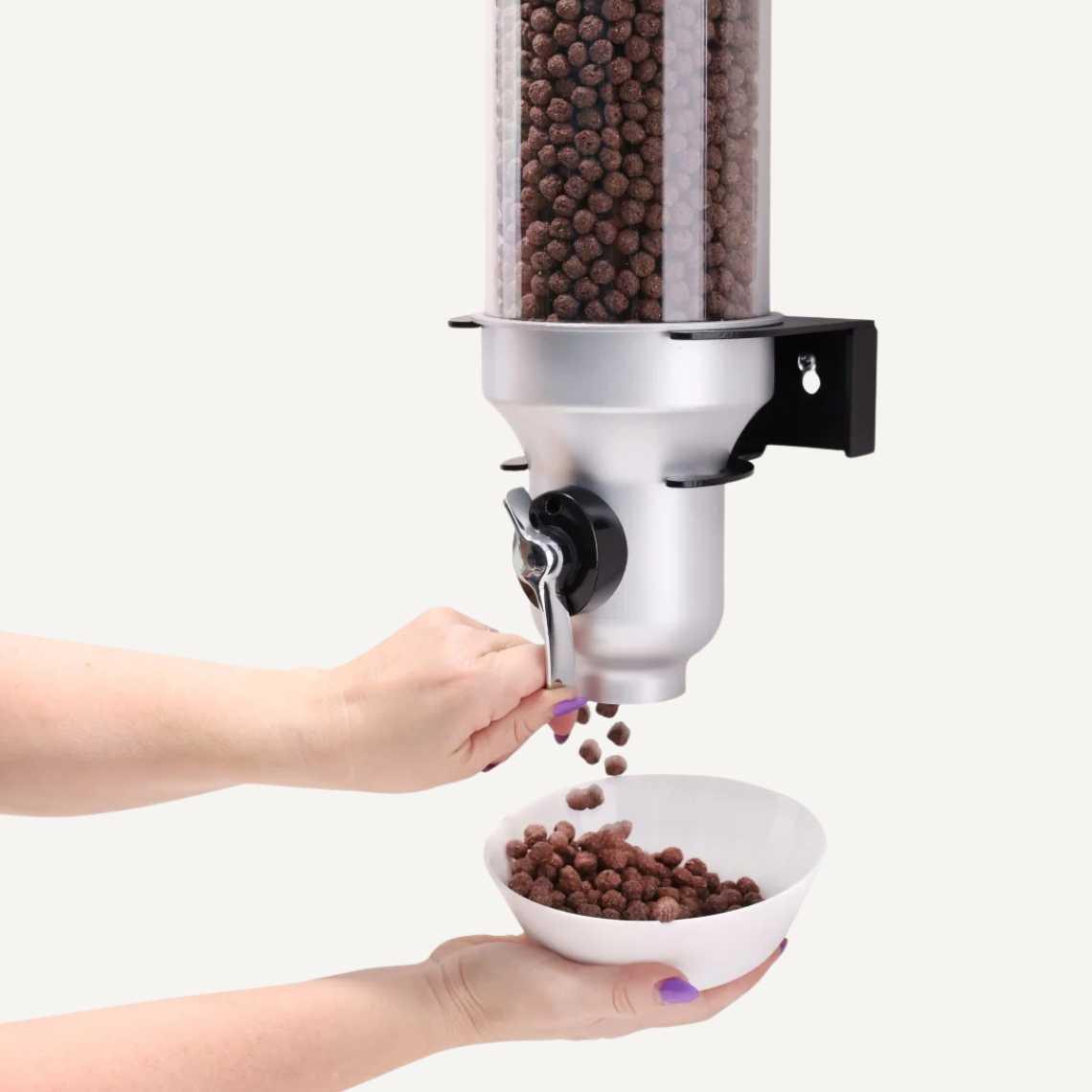 A black and silver cereal dispenser dispensing chocolate cereal into a bowl.