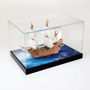 A model sailing ship inside a custom display case with a sea like printed base.