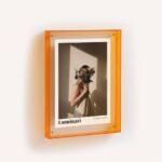 A bright orange acrylic frame with a print inside.