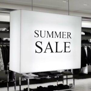 A ceiling hanging illuminated sign in a clothes shop with "summer sale" printed on it.