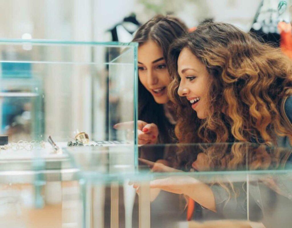 Two women looking and pointing at jewellery in a clear case.