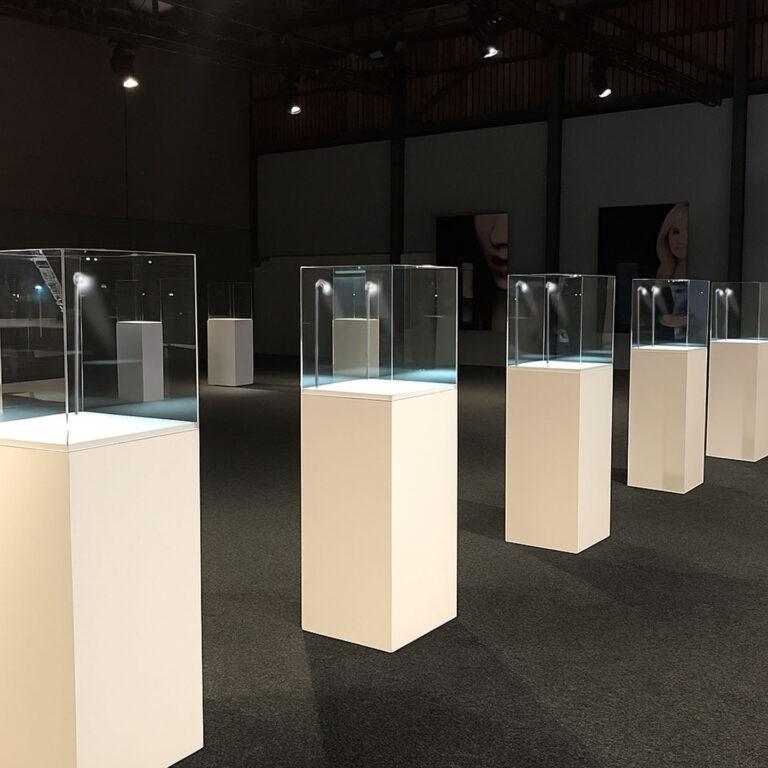 White Display Plinth Pedestals with clear display case on top and LED spot light in an exhibition studio.