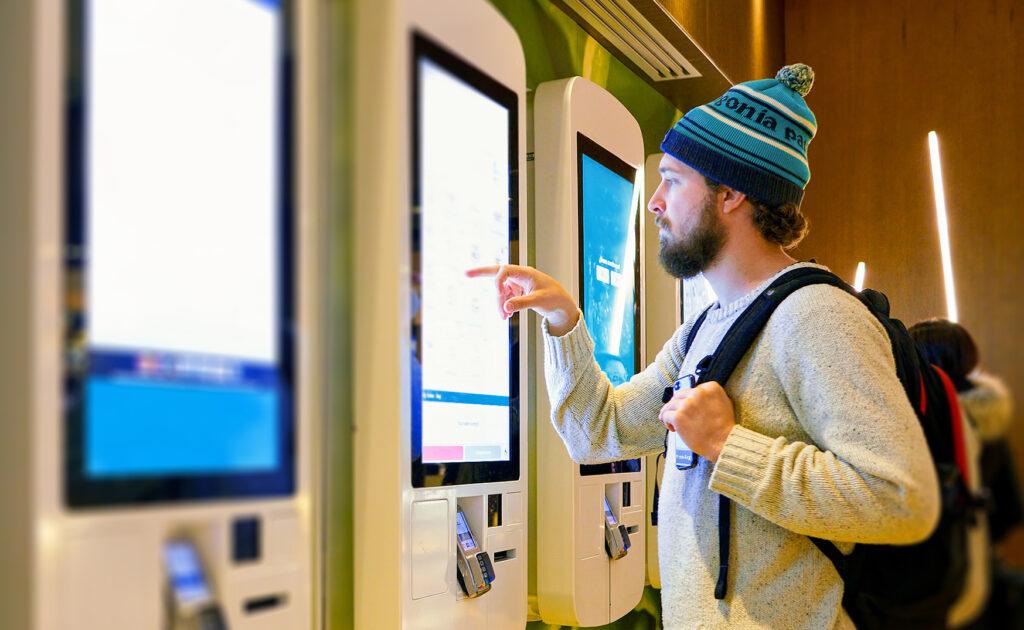 A man using a touch screen self-service kiosk.