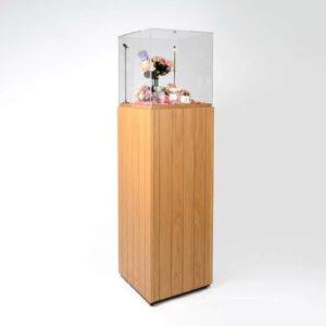 A wooden plinth with protective cover and flowers on display.