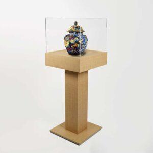 A wooden plinth pedestal with a protective cover and vase on display.