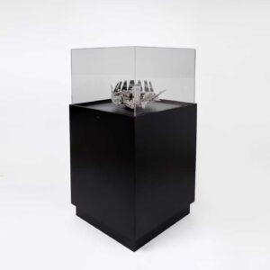 A black display plinth with a decorative object on display.