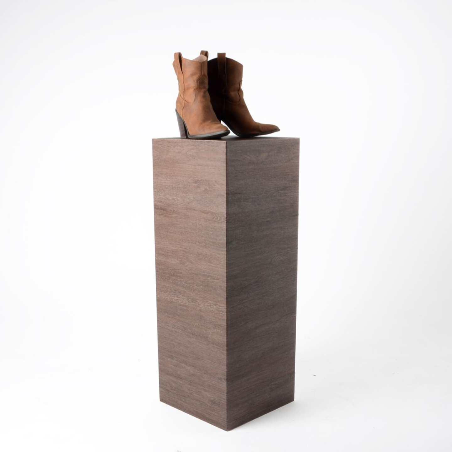 A wood effect standard plinth with brown boots sat on top.