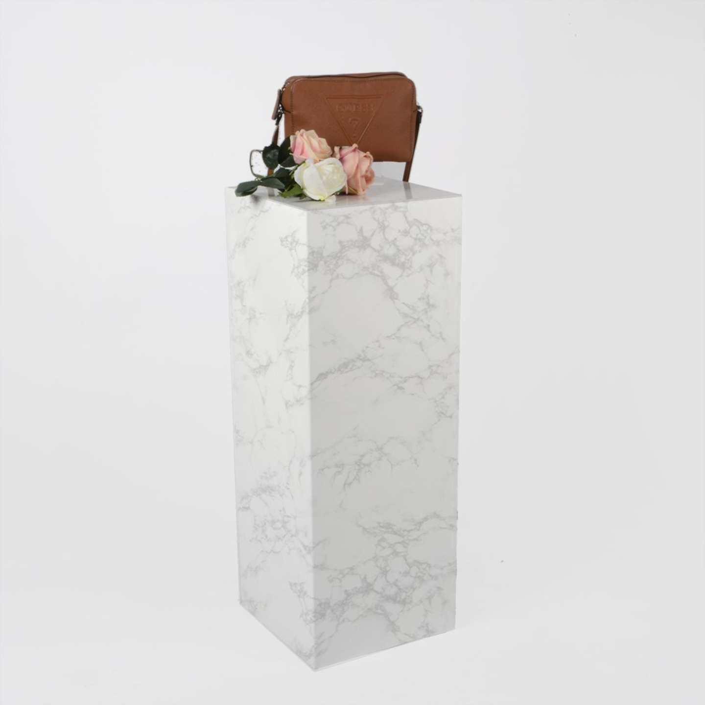 A marble effect standard plinth with products on top.