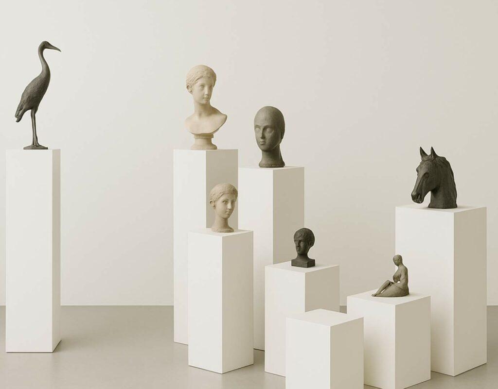 A display of different sized white plinths with sculptures on top.