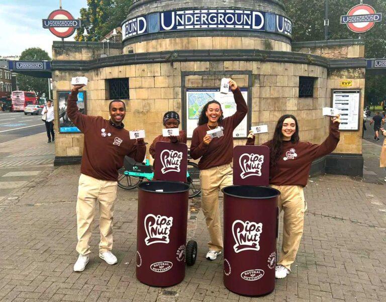People smiling handing out testers in a street outside the London underground.