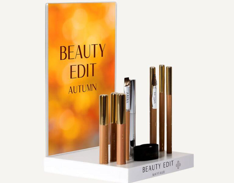 A countertop makeup display with interchangeable header pocket and makeup on display.