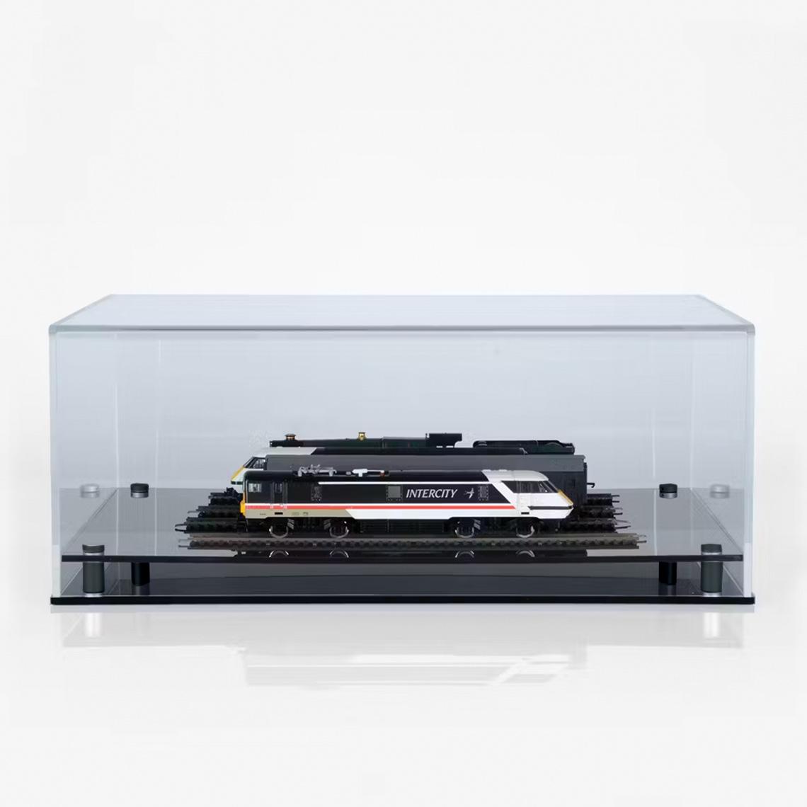Clear acrylic rectangular display case featuring two model trains on parallel tracks mounted on a glossy black base, set against a light background.