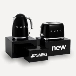 Three black gloss countertop plinths with a SMEG toaster and kettle on display and custom branding on the plinths.