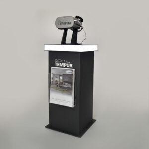A Dark Grey TEMPUR-branded display plinth featuring an illuminated white top surface, a VR headset mounted on top, and a clear front brochure holder containing a TEMPUR catalogue.