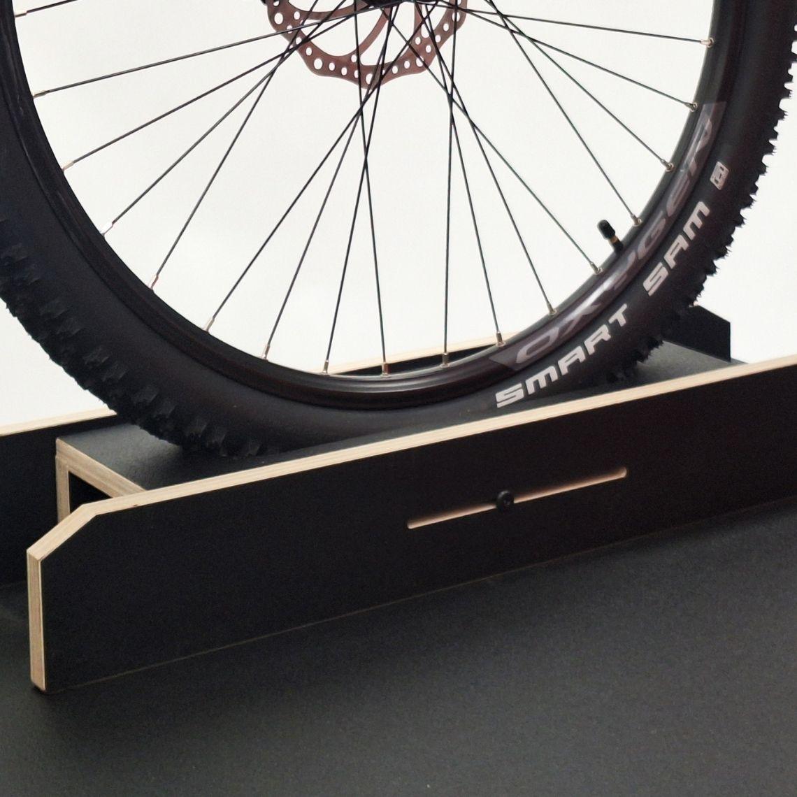 Front wheel support of the bike display podium featuring adjustable slidable slots and durable black melamine plywood construction.