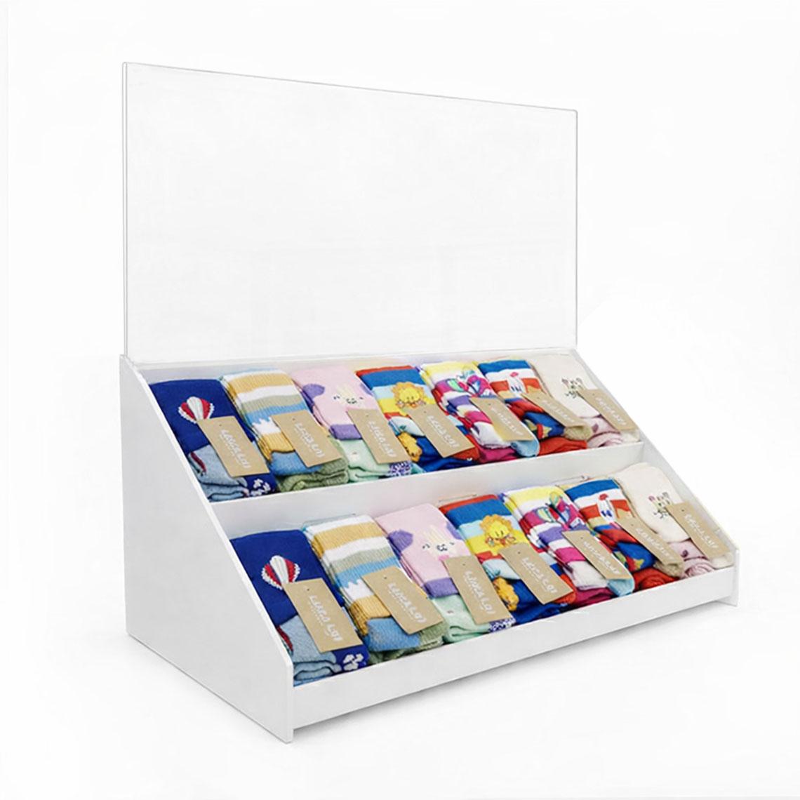 White countertop point of purchase display with two-tier shelving and a clear acrylic graphic trap header for interchangeable retail signage.