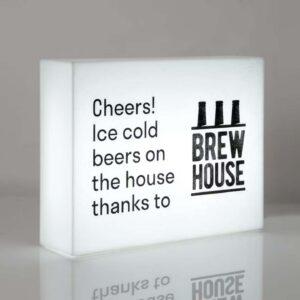 A frameless illuminated lightbox with text and a logo written on the front.