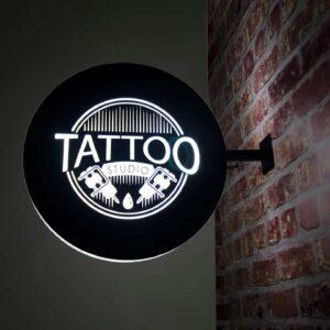 A double sided circular lightbox attached to a brick wall.