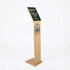 A silent salesman made from birch plywood with a logo on the front and a please wait to be seated sign in the graphics trap.